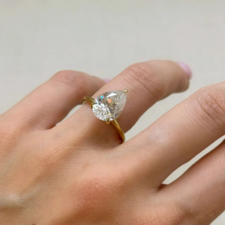 verlobungsring-royal-stones-moissanit-4ct-tropfenschliff-am-finger-nahaufnahme-gelbgold-glitare-hariets.jpg