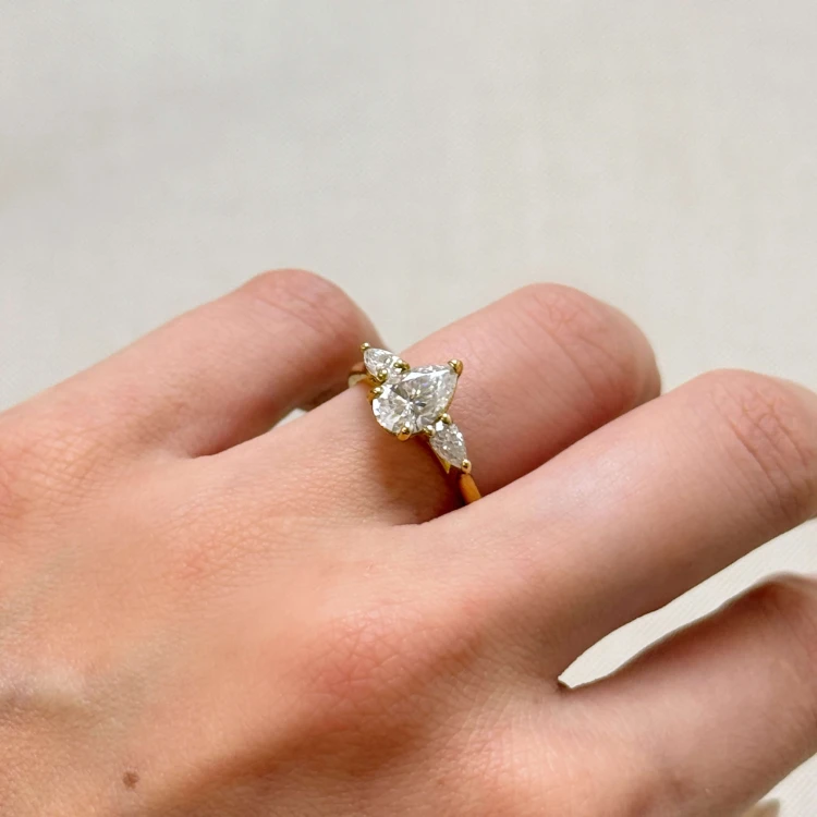 verlobungsring-trinity-amara-moissanit-1-5ct-zentraler-tropfenschliff-am-finger-seite-gelbgold-hariets.JPG
