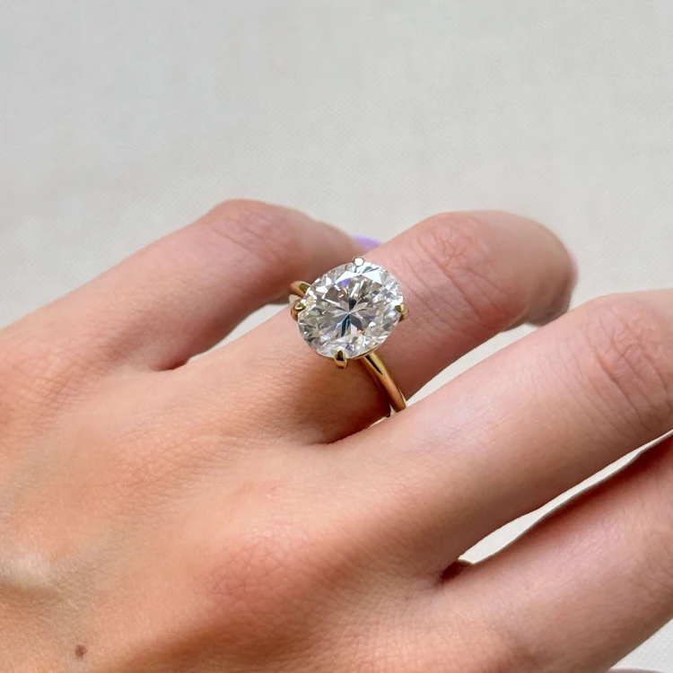 verlobungsring-royal-stones-moissanit-5ct-ovalschliff-nahaufnahme-am-finger-gelbgold-paris-hariets.jpg
