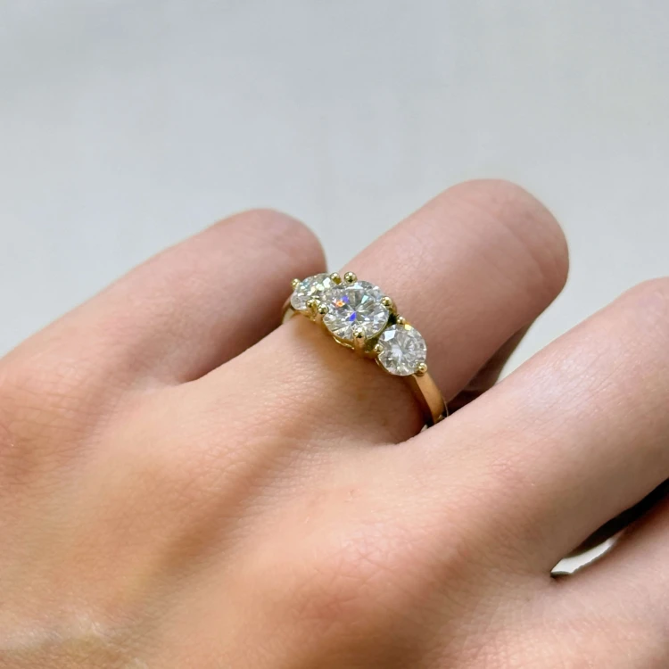 verlobungsring-trinity-moissanit-2ct-brillantschliff-am-finger-nahaufnahme-gelbgold-trigem-hariets.jpg