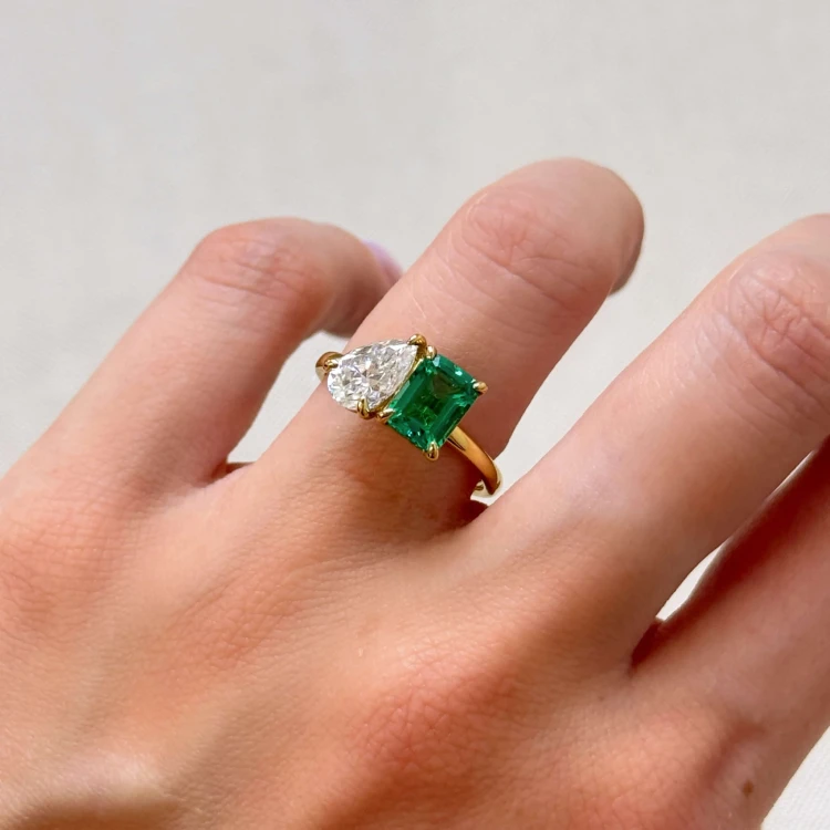 verlobungsring-toi-et-moi-hydrothermaler-smaragd-3-5ct-emeraldschliff-birnschliff-am-finger-nahaufnahme-gelbgold-gemini-hariets.jpg