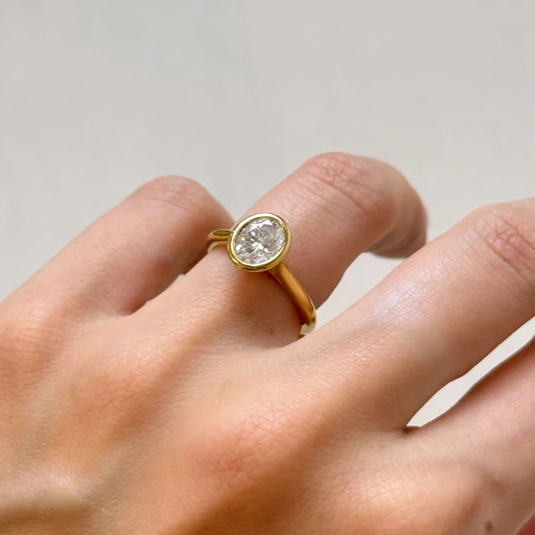 verlobungsring-bezel-moissanit-1-2ct-ovalschliff-am-finger-gelbgold-amora-hariets.jpg