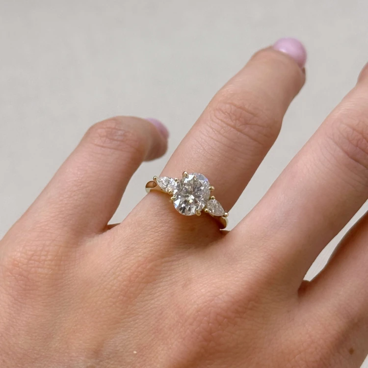 Verlobungsring-Trinity-Seraphina-labordiamant-2ct-ovalgeschliffener-Mittelstein-am-Finger-Gelbgold-Hariets.jpg