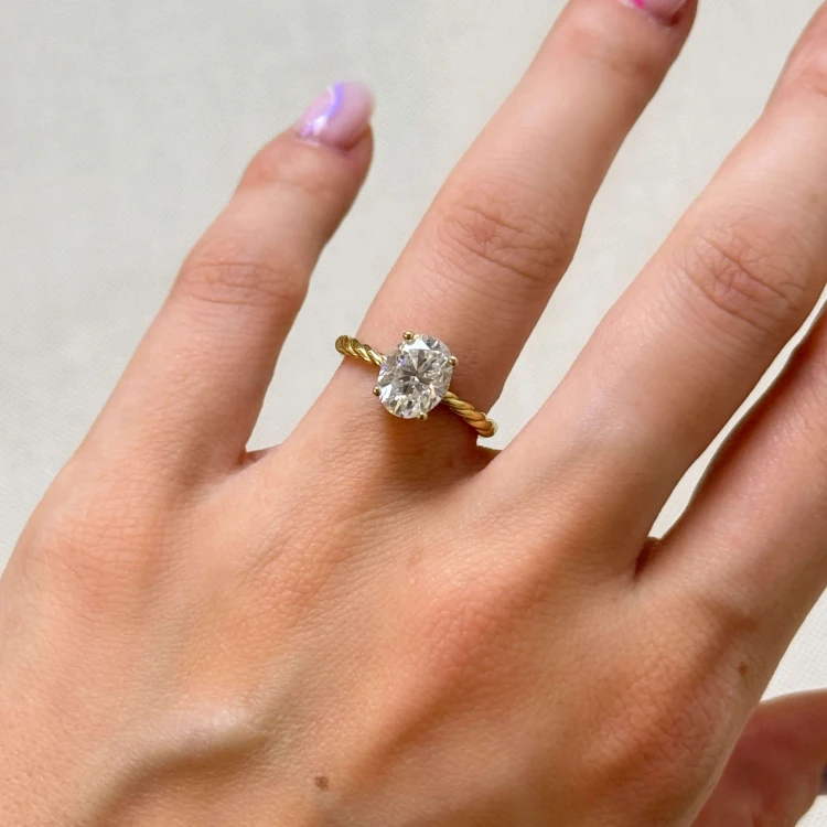 verlobungsring-mit-gedrehtem-ringband-labordiamant-2ct-ovalschliff-am-finger-nahaufnahme-gelbgold-twisted-hariets.jpg