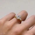 Verlobungsring-Trinity-Seraphina-Moissanit-2ct-ovalgeschliffener-Mittelstein-Seitenansicht-am-Finger-Gelbgold-Hariets.jpg